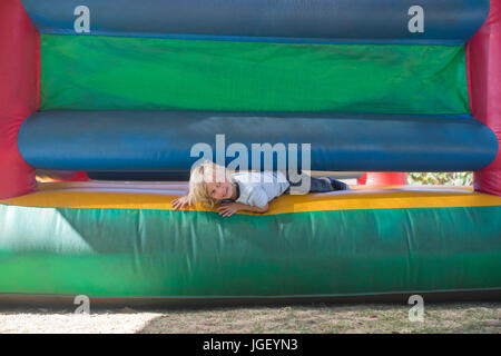 Portrait of happy boy playing on bouncy castle at playground Stock Photo