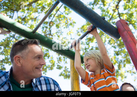 Low angle view of father and son looking at each other while playing on jungle gym Stock Photo