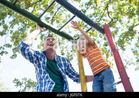 Low angle view of father and son playing on jungle gym at playground Stock Photo