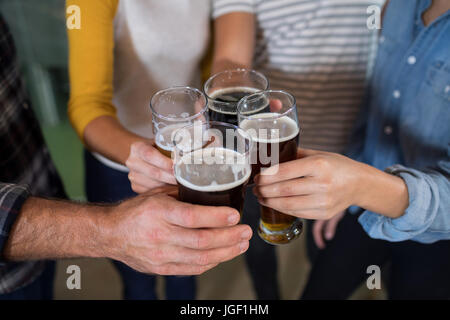 Cropped hands of friends toasting drinks at factory Stock Photo
