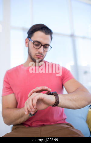 Male executive checking time on smartwatch in the office Stock Photo