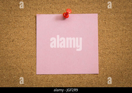 Blank note paper with a red push pin on cork board. Stock Photo