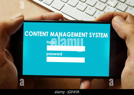 Hands holding phone with Content Management System  CMS. Stock Photo
