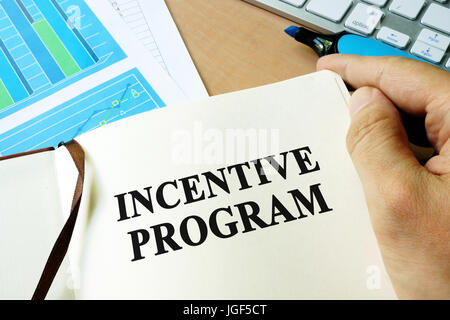 Hands holding book with title Incentive program. Stock Photo