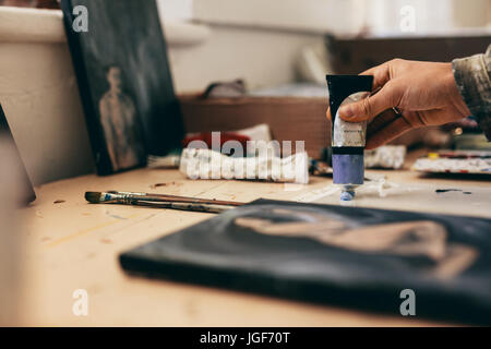 Close up of female artist hands with colors. Cropped shot of woman getting paint from tube in her studio. Stock Photo