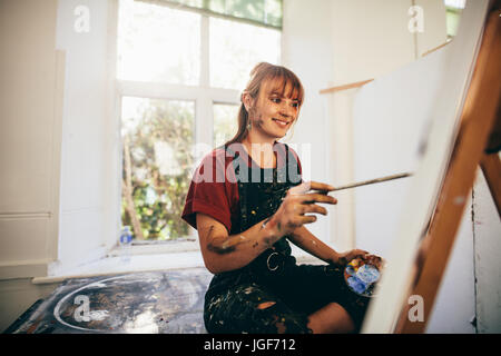 Indoor shot of female artist painting in studio. Woman painter painting in her workshop. Stock Photo