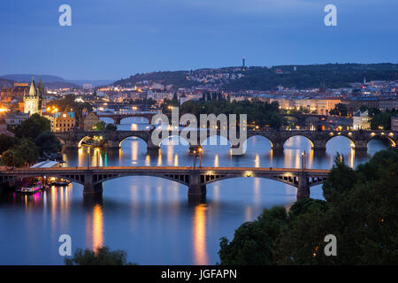 Lit buildings and bridges over Vltava River in Prague, Czech Republic, viewed slightly from above at dusk. Stock Photo