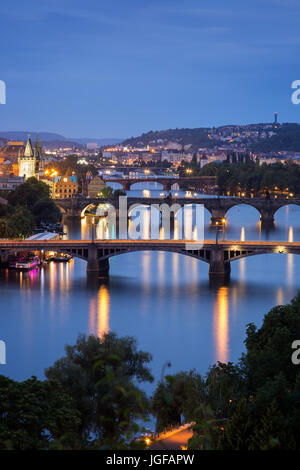 Lit buildings and bridges over Vltava River in Prague, Czech Republic, viewed slightly from above at dusk. Stock Photo