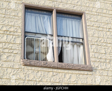 Box fan in window of an old apartment building Stock Photo