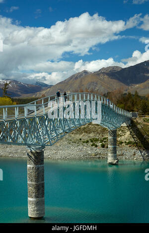 Tourists on pedestrian Bridge over Lake Tekapo outlet to Church of the Good Shepherd,  Mackenzie Country, Canterbury, South Island, New Zealand Stock Photo