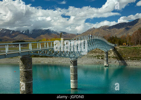 Tourists on pedestrian Bridge over Lake Tekapo outlet to Church of the Good Shepherd,  Mackenzie Country, Canterbury, South Island, New Zealand Stock Photo