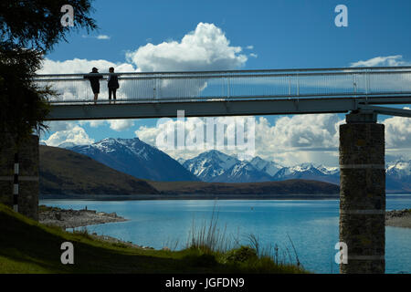 Tourists on pedestrian Bridge over Lake Tekapo outlet to Church of the Good Shepherd,  Mackenzie Country, Canterbury, South Island, New Zealand Stock Photo