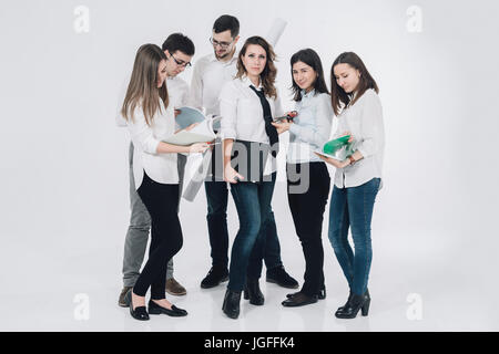 Caucasian woman holding laptop near co-workers reading paperwork Stock Photo