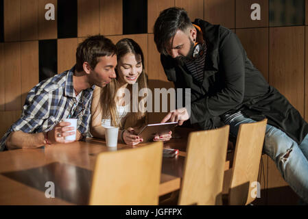 Group of friends sitting in the room by the table and comunicate. Stock Photo
