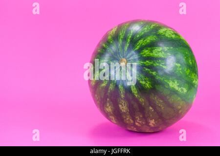 Tiny watermelon isolated on fuchsia background Stock Photo