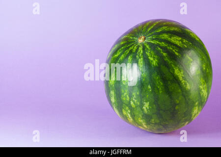 Tiny watermelon isolated on lilac background Stock Photo