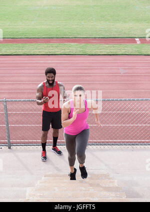 Trainer timing woman running on bleachers Stock Photo