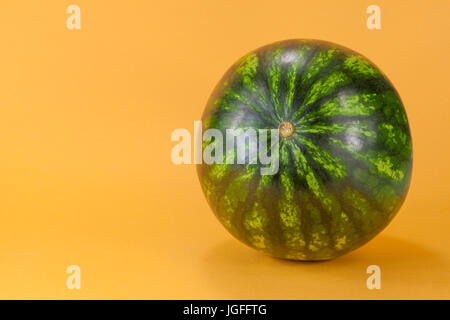 Tiny watermelon isolated on orange background. Stock Photo