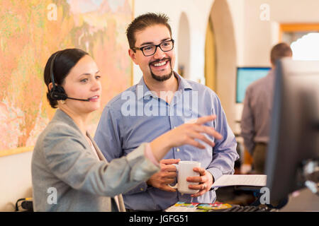 Co-workers talking in office near computer Stock Photo