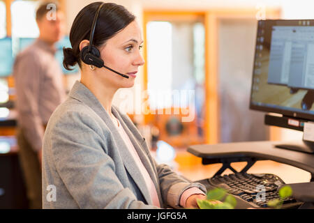 Caucasian businesswoman wearing headset using computer Stock Photo