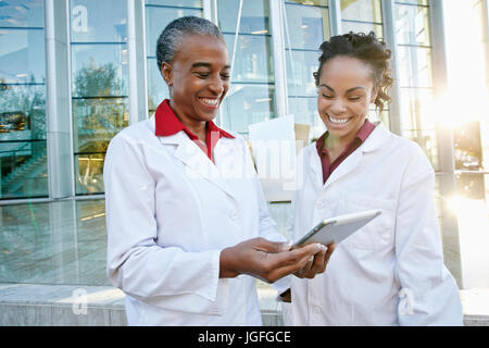 Doctors outdoors at hospital using digital tablet Stock Photo