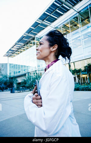 Portrait of smiling Mixed Race doctor holding digital tablet outdoors Stock Photo