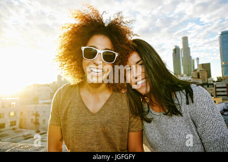 Portrait of smiling Hispanic women on urban rooftop at sunset Stock Photo