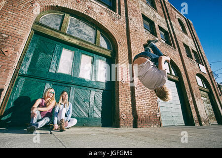 Woman watching man skateboarding on urban sidewalk Stock Photo