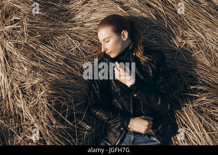 Middle Eastern woman resting in tall grass Stock Photo