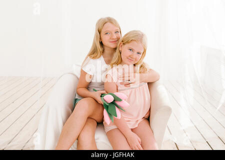Portrait of smiling Middle Eastern sisters in armchair Stock Photo