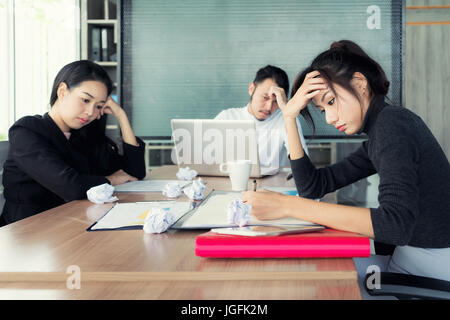 Group of unhappy Asian business people in casual suit sitting in business meeting room and looking strain. Stock Photo