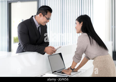 Asian businessman check in at hotel reception front desk. Stock Photo