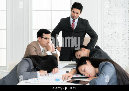 Boss angry when business people team sleeping on meeting room in office. Business people team tired after working hard. Stock Photo