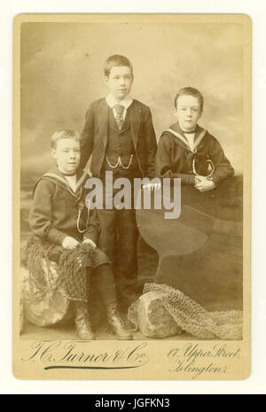 Original sepia-toned Cabinet card studio portrait with seaside backdrop of 3 young Victorian boys posing in sailor suits, dated 1888, Islington, London, U.K. Stock Photo