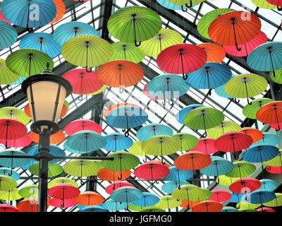 Multi colored umbrellas hanging from a ceiling in a mall Stock Photo