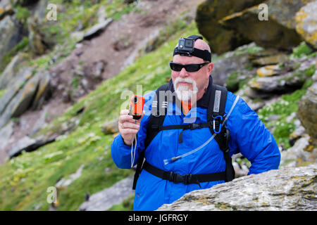 Man wearing GoPro Hero headcam and holding Fuji Finepix XP camera Stock Photo