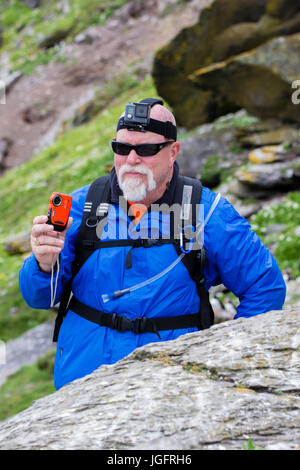 Man wearing GoPro Hero headcam and holding Fuji Finepix XP camera Stock Photo