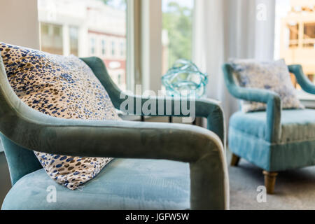 Closeup of two new modern blue couch chairs by windows with natural light and pillows Stock Photo
