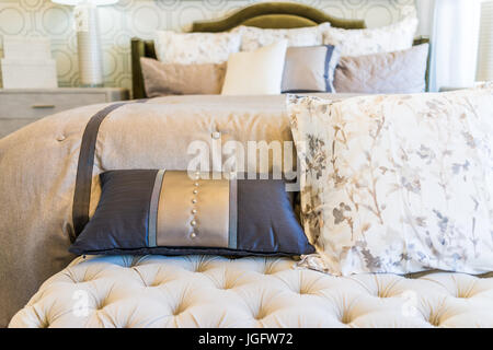 Modern decorated bed with bench rest and many pillows closeup Stock Photo