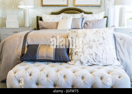 Modern decorated bed with bench rest and many pillows closeup Stock Photo