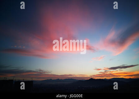 Beautiful natural sunset sunrise over silhouettes city skyline and amazing orange cloud blue sky above it . Stock Photo