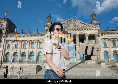 Berlin, Germany. 06th July, 2017. Katja from Russia takes a selfie with her smartphone while holding a German flag in front of the Reichstag (Federal Legislature) in Berlin, Germany, 06 July 2017. Photo: Paul Zinken/dpa/Alamy Live News Stock Photo