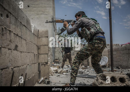 Fighters of the People's Protection Units (YPG), a mainly-Kurdish militia in Syria, fires their guns towards positions of militants of the so called Islamic State (IS) in Al Sinaa neighborhood, eastern Raqqa, Syria, 06 July 2017. Syrian activists say Islamic State group fighters are battling to repel the advance of U.S.-backed Syrian forces days after they brought the fight to the heart of the militant group's de-facto capital. Photo: Morukc Umnaber/dpa Stock Photo