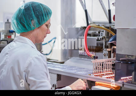 Robotic arm lifting ampoules at packaging line in pharmaceutical factory. Stock Photo