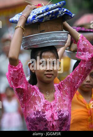 Woman carrying offerings on her head during a traditional hindu temple festival procession, Bali island, Canggu, Indonesia Stock Photo