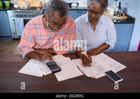 High angle view of couple using calculator in kitchen at home Stock Photo