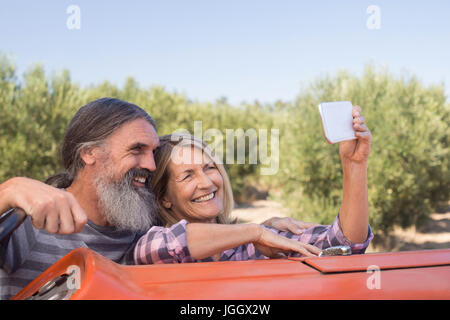 Happy couple taking selfie from mobile in olive farm Stock Photo