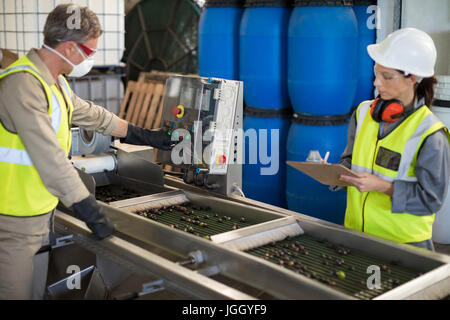 Technicians operating machine while processing olives in factory Stock Photo
