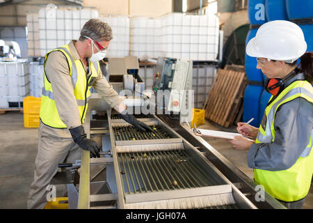 Technicians examining olives on conveyor belt in oil factory Stock Photo