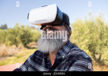 Happy man using virtual reality headset in olive farm on a sunny day Stock Photo